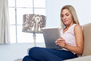 Woman at home relaxing on sofa couch reading email on the tablet computer wifi connection